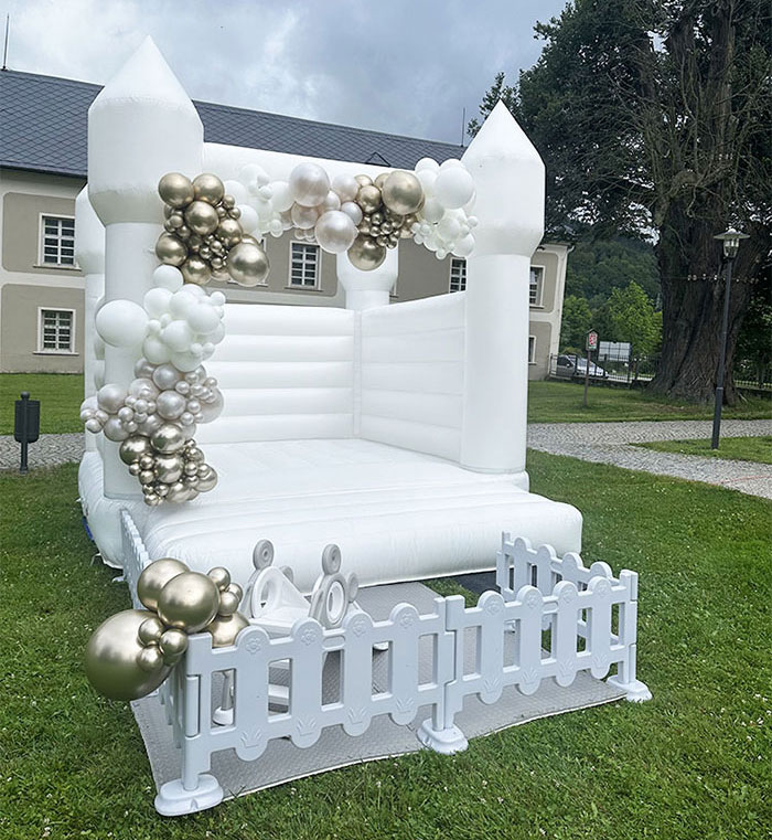 Bílý svatební skákací hrad s elegantní balónkovou dekorací.